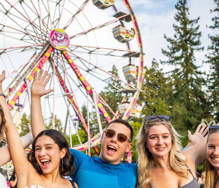 Five students with hands up in the air and excited